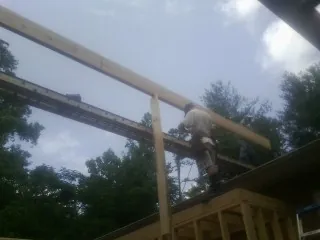 Carpenter setting a ridge beam over a new addition frame — Ice Dam Removal by Roofing Brothers in Thompson Ridge