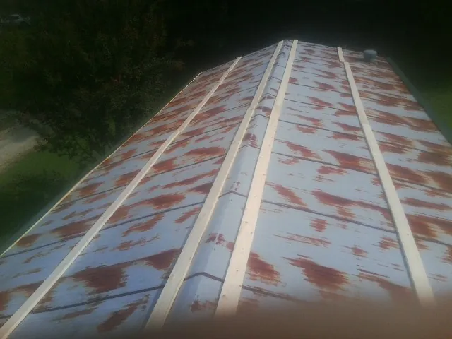 Rusted metal roof panels with new wood purlins before replacement — Storm Damage Roof Repair in Thompson Ridge by Roofing Brothers