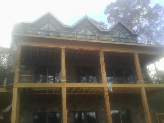 Dormers and porch framing on a large log home under construction — Roof Coating work by our crew in Thompson Ridge
