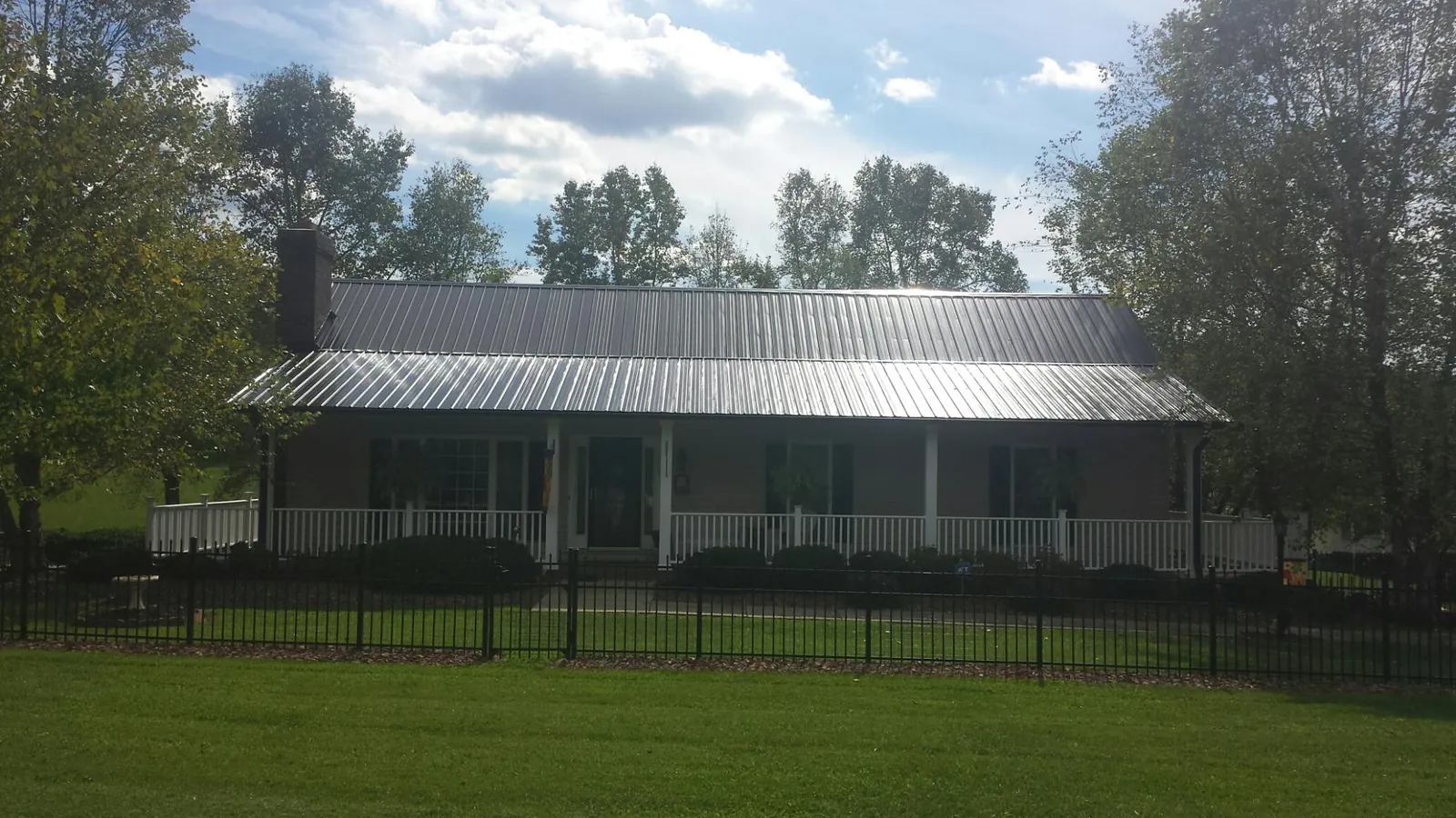 Gray metal roof on a brick ranch with a full width front porch — Gutter Guard Installation work by our crew in Thompson Ridge