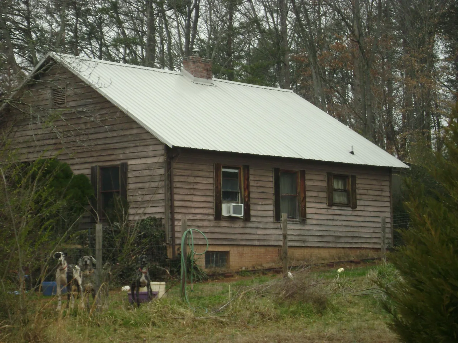 White metal roof on an old wood sided farmhouse, from a Metal Roof Installation job in Thompson Ridge