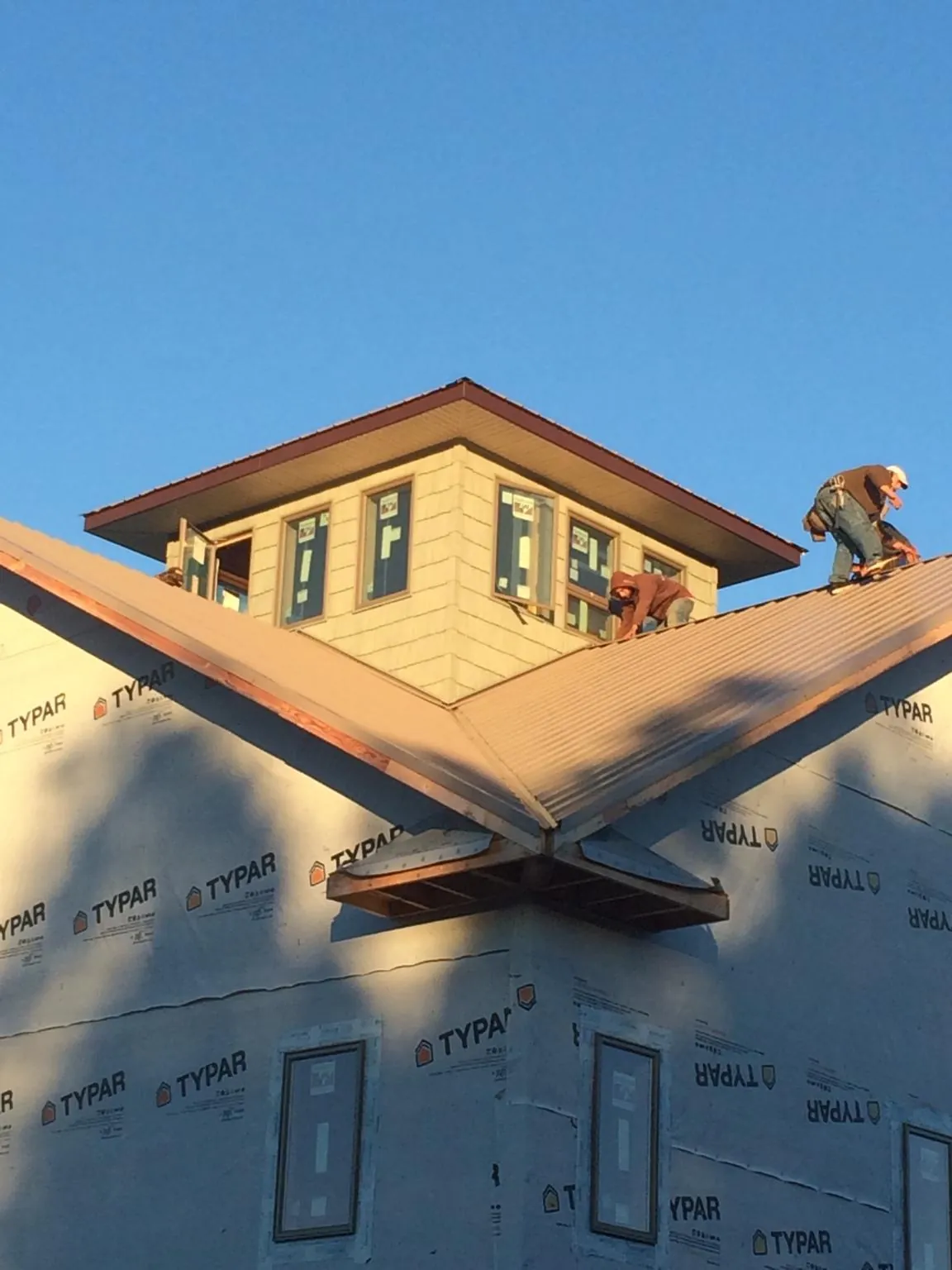Roofers working around a rooftop cupola on a new metal roof at sunset — Roof Waterproofing in Thompson Ridge by Roofing Brothers